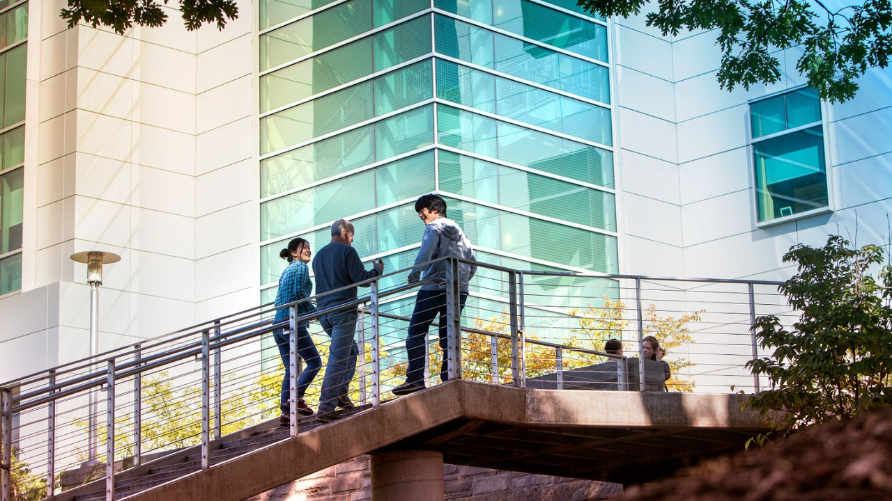 Three figures walk up a staircase on Cornell's campus.